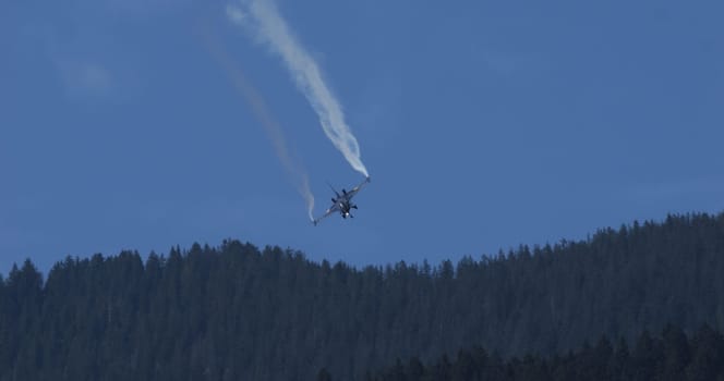 Stunning Fighter Jet in Sunny Alpine Valley Flight. Blue Sky and Smoke Trails