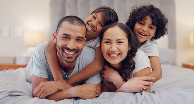 Portrait, happy and kids with parents in bed relaxing and bonding together at family home. Smile, fun and young mother and father laying and resting with children in bedroom of modern house.