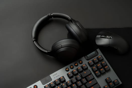 Headphones, computer mouse and keyboard on black background