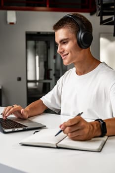 Young man wearing headphones while studying with laptop close up
