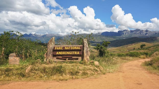 Andringitra National Park, Madagascar - April 27, 2019: Sign at the entrance road to park, mountain massif in distance with dramatic clouds above. Pic Boby aka. Imarivolanitra, highest peak - is there