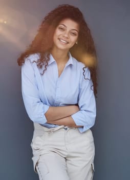 Smiling attractive young business woman in blue shirt posing on gray background