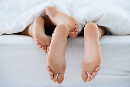 Couple, morning or feet with blanket in sleeping for peace or rest together on weekend in a house. Wellness, comfort or closeup of barefoot people in home for bond, care or nap under duvet in bedroom