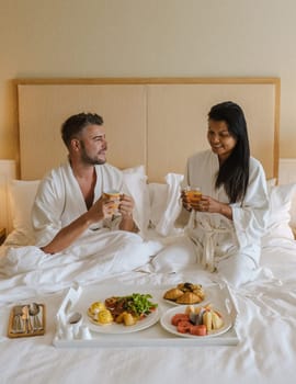 couple having breakfast in bed at an luxury hotel, men woman in bed with breakfast coffee and bread