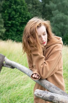 young beautiful woman posing in a brown sweater in the village
