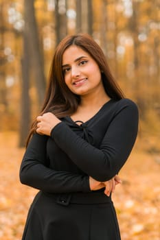 Close up portrait of pretty indian young woman enjoying warm autumn sunny day vacation outdoors. Generation z and gen z concept. Fall Season