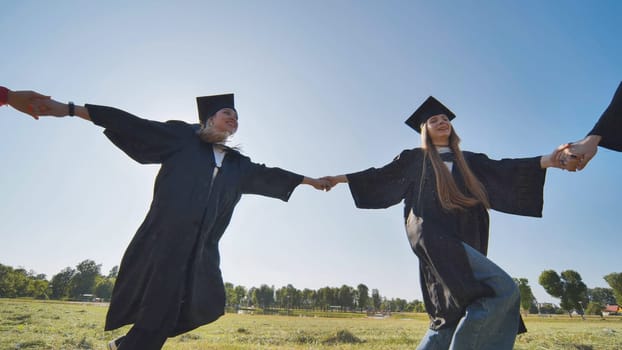 College graduates holding hands run in a round dance.