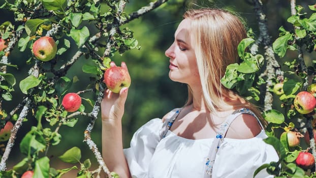 A young woman in paradise posing by the branches of an apple tree.