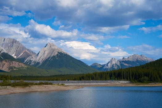 An incredible view of a natural mountain lake on a sunny summer day against the backdrop of the rocky mountains of Alberta in Canada.