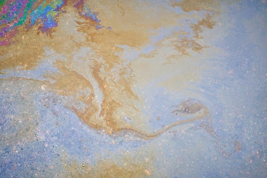 An oily iridescent stain of gasoline or oil spilled on the road.
