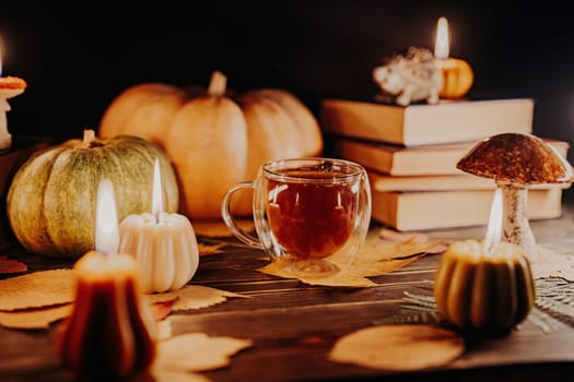 Glass cup of tea among pumpkin candles. Autumn-themed content, cafe promotions