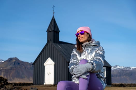 Woman with metallic coat in the black chapel of Budakirkja, Iceland