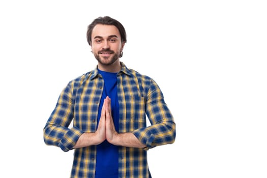 handsome brunette macho man with a beard in a blue shirt on a white background actively gesturing with his hands with copy space