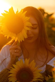 A girl in a hat on a beautiful field of sunflowers against the s