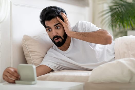 Late For Work. Shocked Overslept Indian Guy Looking At Alarm Clock
