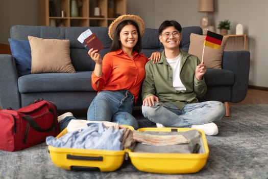 Asian Tourists Couple With Germany Flag Packing Suitcase At Home