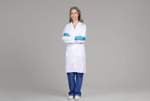 Full Length Of Doctor Woman Wearing Coat On Gray Background