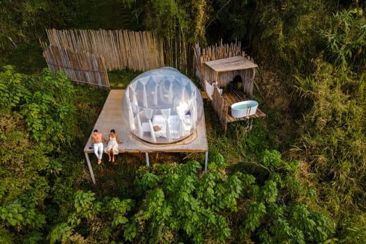 couple man and women in a bubble tent with an outdoor bathroom with bath in the jungle rainforest