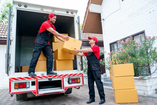 Wide shot of delivery man stand on truck and send parcel or box to his co-worker during transport the product to customer house.