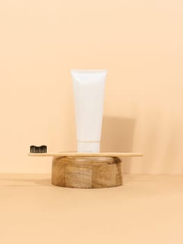 White plastic toothpaste tube and wooden toothbrush on a beige background. 