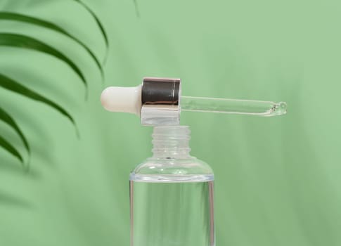 Glass bottle  for cosmetics, oils with a pipette on a green background