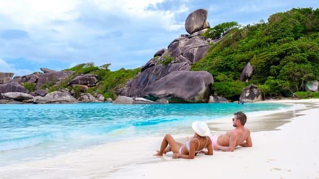 Asian women and white men relaxing on the beach in the sun at the Similan Islands Thailand
