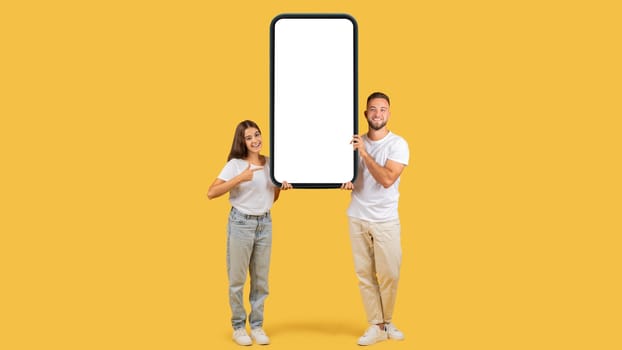 A young woman and man happily display a large vertical smartphone