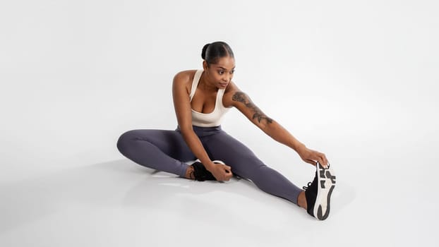 athletic black woman in sportswear has workout in white studio
