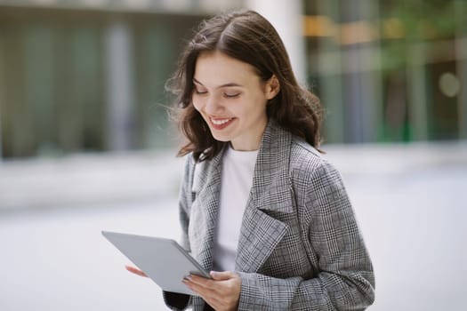 Young business lady browsing through her tablet computer outside