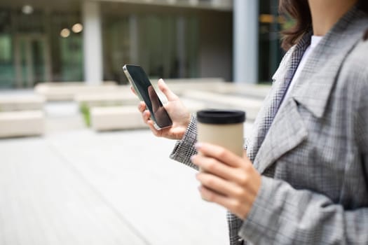 Cropped Shot Of Woman Using Mobile Phone Holding Coffee Outdoor