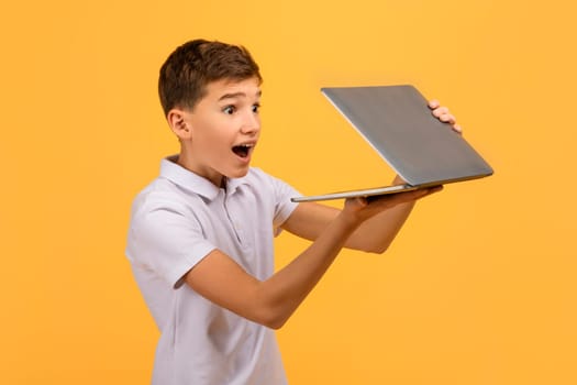 Amazed teen boy opening laptop in his hands
