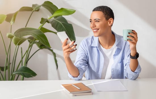 Happy young woman in a light blue shirt multitasking with a smartphone