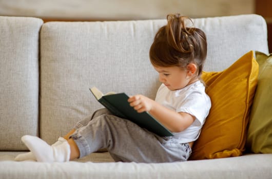 Cute Little Girl Relaxing On Couch With Interesting Book