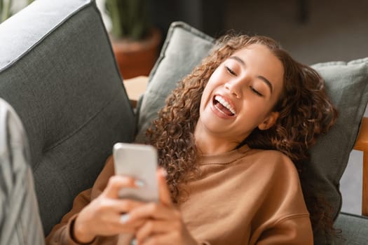 Caucasian teenager girl laughing browsing social media on smartphone indoor