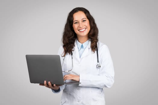 Doctor woman holding laptop with pleasant smile