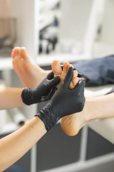 Woman doing foot peeling in pedicure SPA salon. Sugar scrub and relax beauty procedure