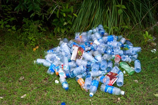 A pile of empty plastic bottles thrown away by tourists in the grass. The problem of ecology and human pollution.