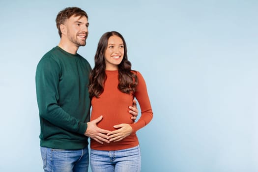 Loving couple with man's hands on pregnant belly, expecting joy