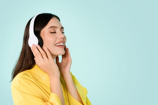 Cheerful millennial brunette woman in casual and wireless headphones
