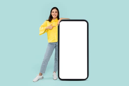 Cool stylish young brunette woman pointing at huge phone