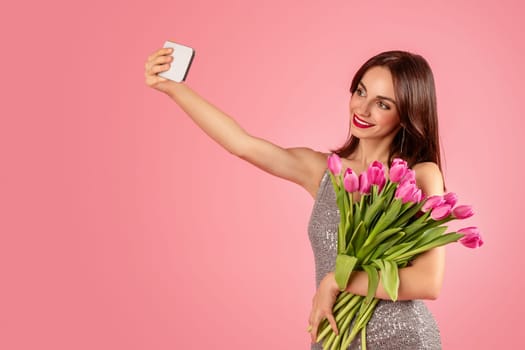 Smiling woman in a sequined dress taking a selfie with her smartphone