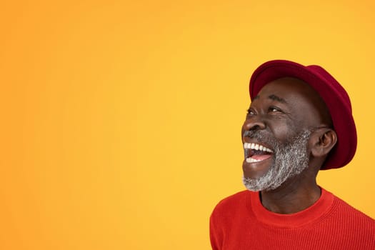 Joyous senior Black man with a white beard, looking up and laughing in delight