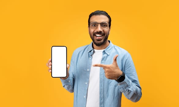 An enthusiastic man with a beard and glasses points at a smartphone with a blank screen
