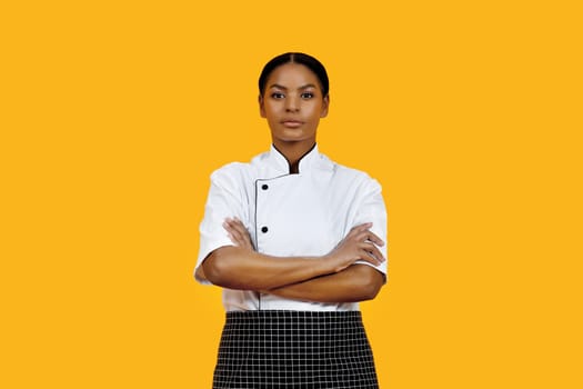 Professional black female chef in white uniform standing with her arms crossed