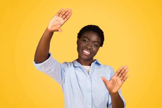 A black woman student playfully making a frame sign with her hands, suggesting creativity