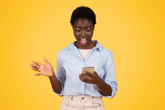 Glad shocked teen black lady student, typing on smartphone, in social networks, enjoy win