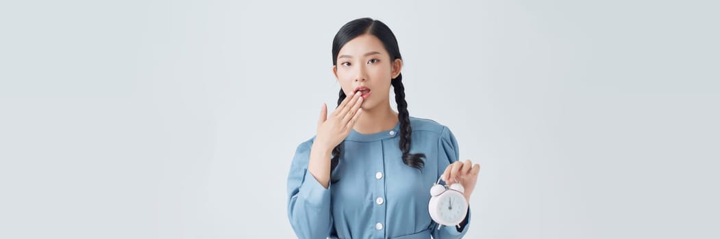 Young Asian woman is stressed with a clock on white background