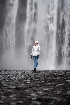 Alone woman with budget raincoat in Skogafoss, Iceland