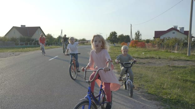 A large family goes on a bike ride in the evening.