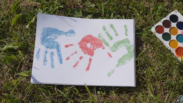 The child leaves a trail of paint with his palm.